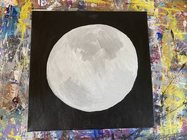 A black canvas with a light gray circle painted in the center of it.